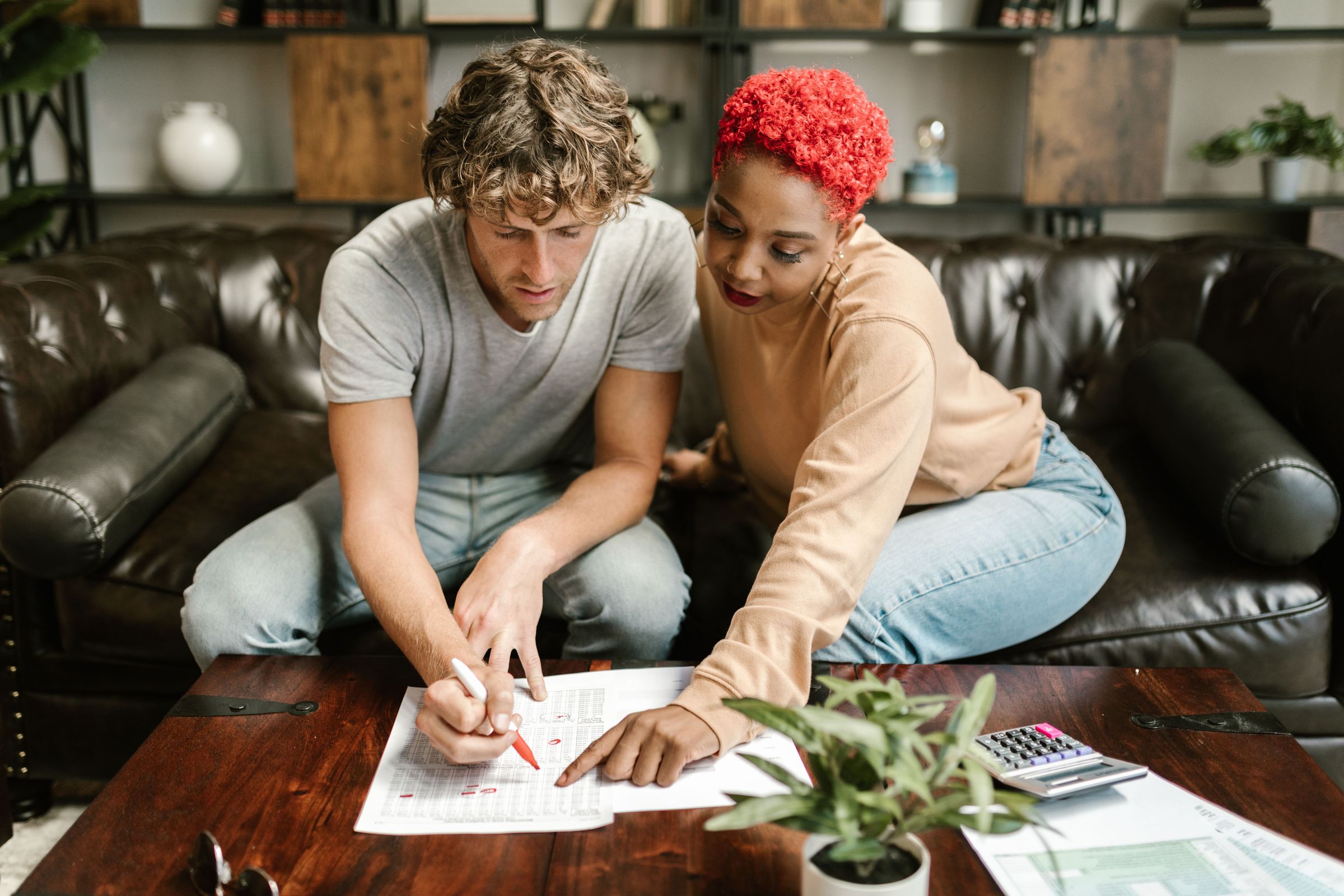 Two adults at a living-room table reviewing a form together.